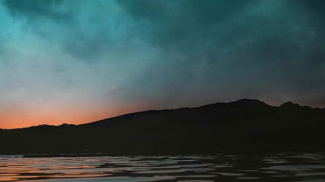 Twilight sky over a silhouetted mountain and lake
