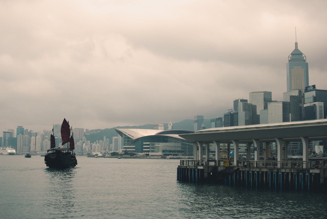 After: Hong Kong harbor with a red-sailed junk boat and the city skyline, edited with the free Cinematic LUTs