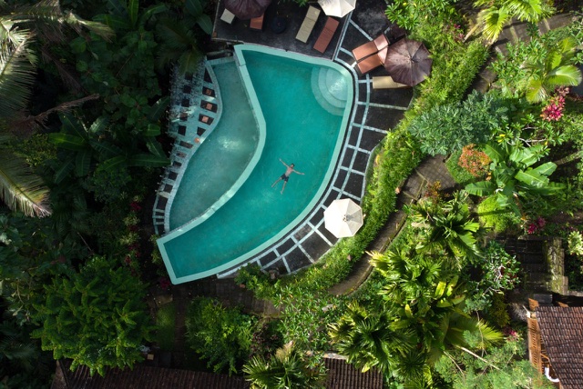 Before: Aerial view of a turquoise swimming pool surrounded by tropical jungle