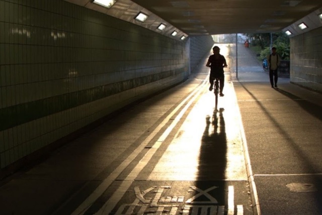 Cyclist riding through a tunnel toward sunlit pavement, before the Urban Pop LUT