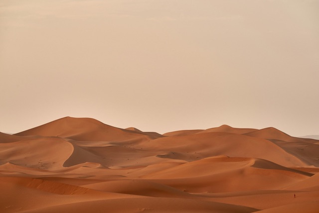 Before: Rolling desert sand dunes under a hazy sky