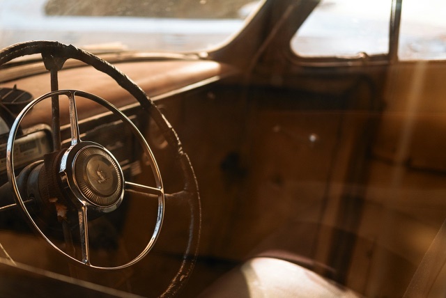 Before: Vintage car steering wheel and dashboard in warm light
