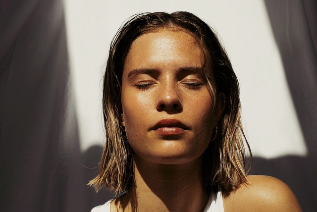 After: Close-up portrait of a woman with eyes closed in sunlight, edited with the free Portrait LUTs