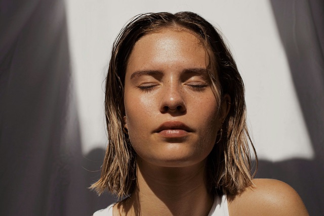 Before: Close-up portrait of a woman with eyes closed in sunlight