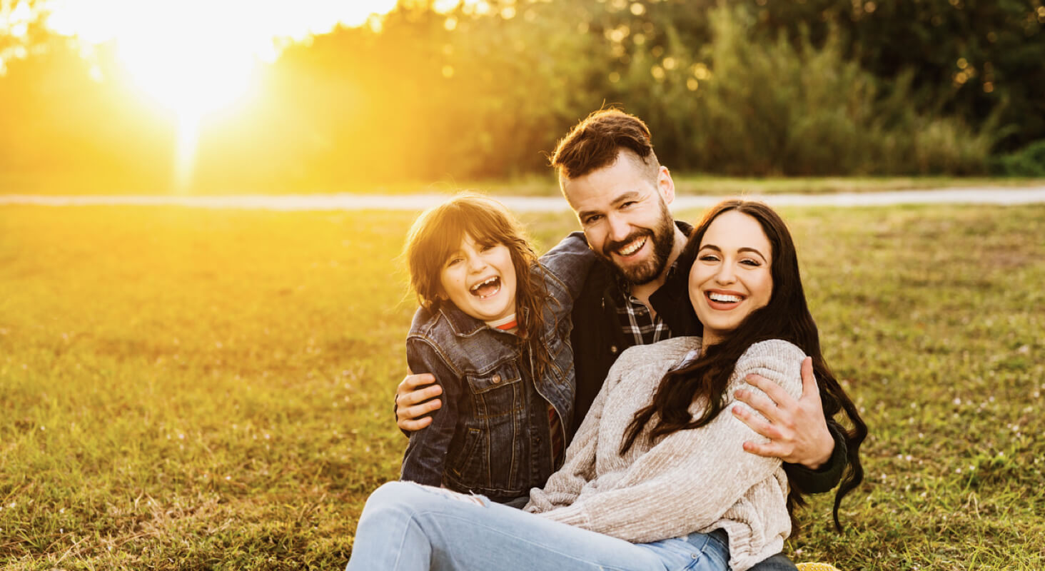 Happy family sitting outdoors at sunset, perfect for lifestyle photo editing software.