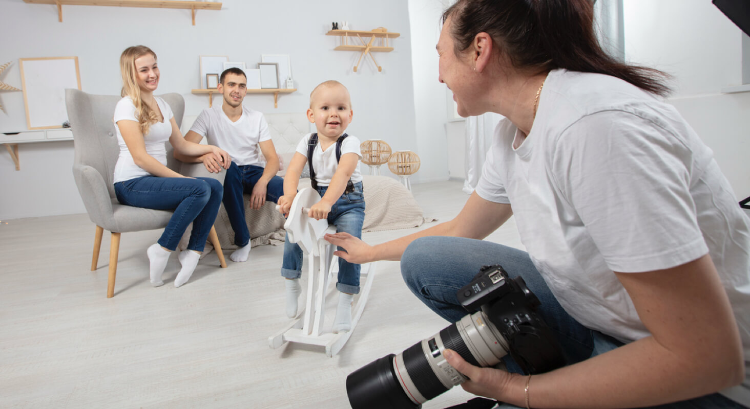 A photographer captures a baby and parents in a studio.