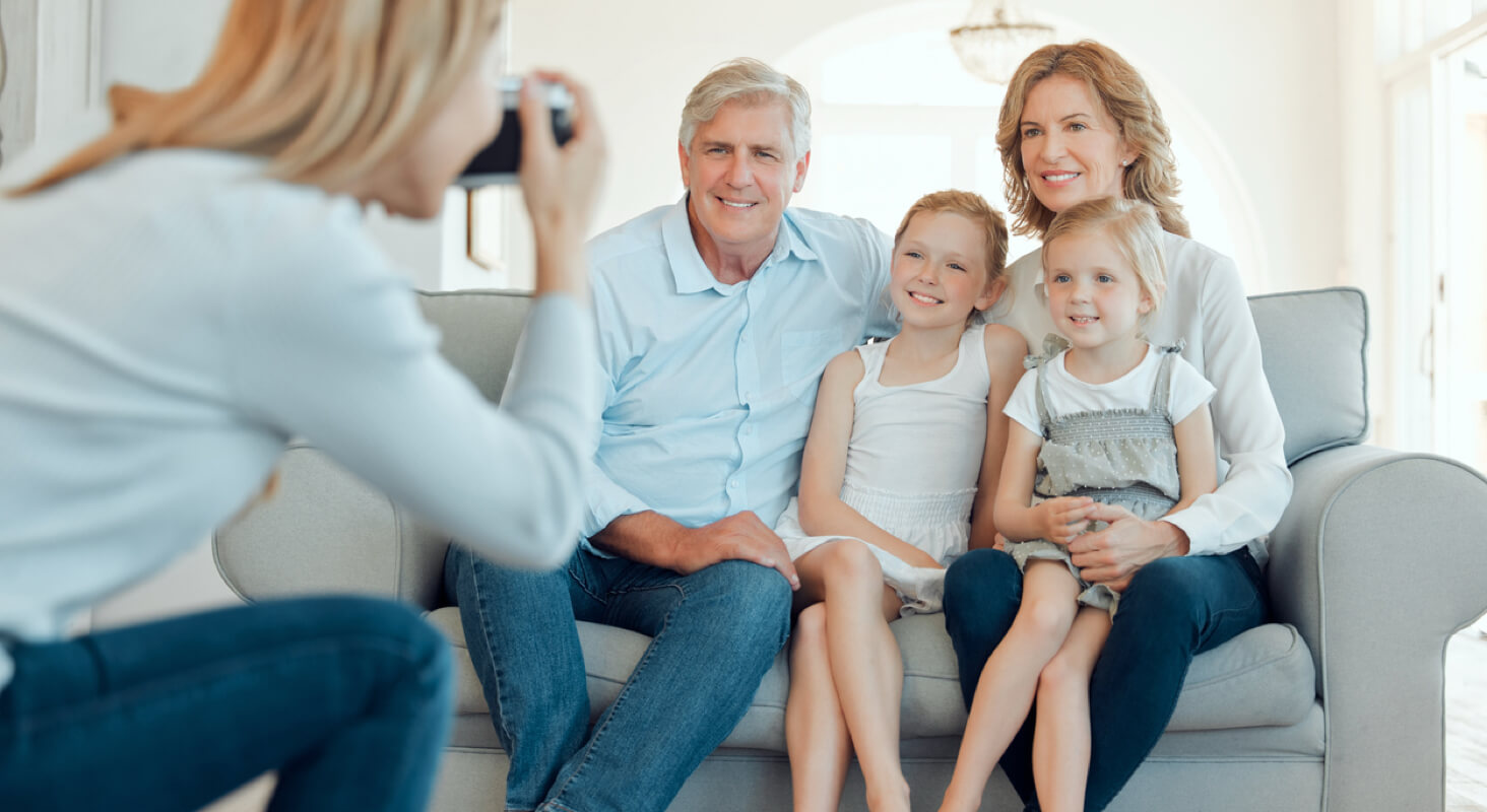Photographer taking a family portrait in a bright living room.