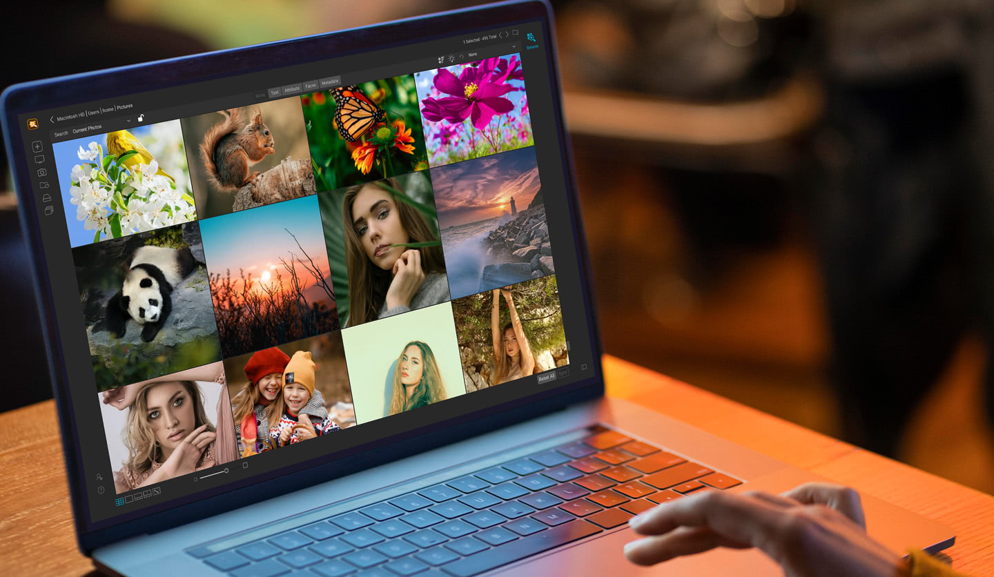 A laptop on a wooden table running Photo Keyword AI, showing a grid of portraits, wildlife, and landscape photos